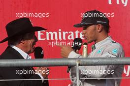 Lewis Hamilton (GBR) Mercedes AMG F1 asks for the hat of Mario Andretti (USA) Circuit of The Americas' Official Ambassador on the podium. 02.11.2014. Formula 1 World Championship, Rd 17, United States Grand Prix, Austin, Texas, USA, Race Day.